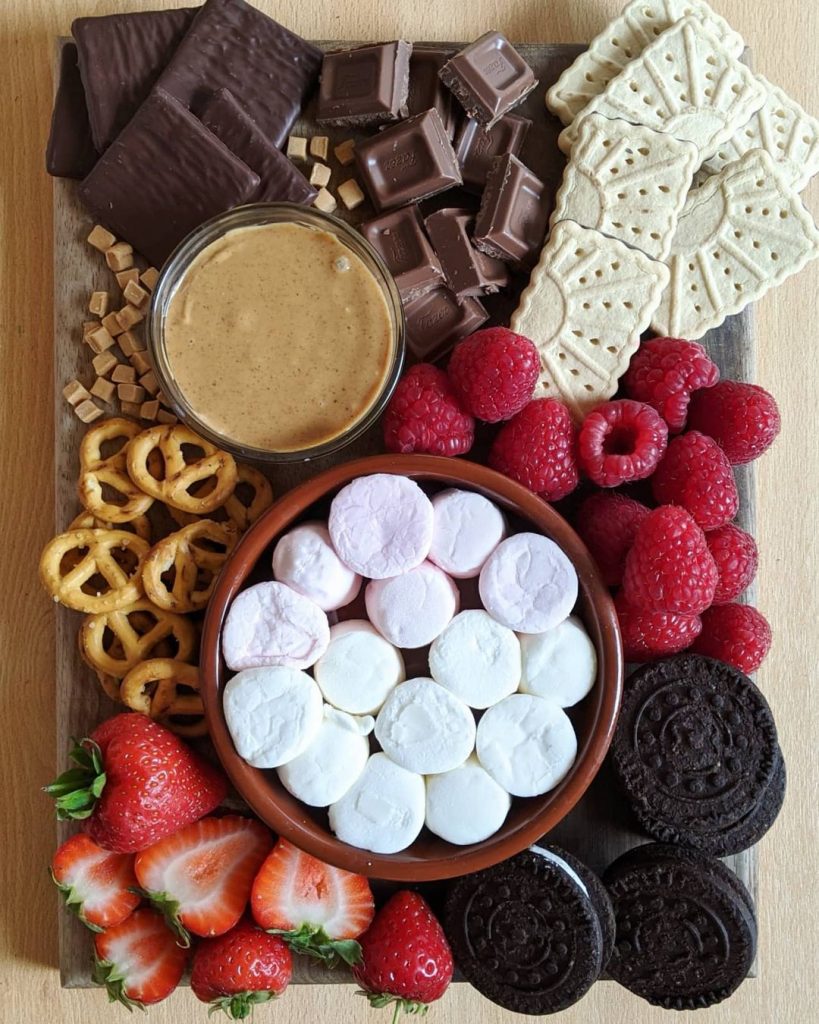 The smores platter has two kinds of chocolate, two kinds of biscuits, halved strawberries, raspberries, pretzels and caramel pieces. It also has a bowl of peanut butter.