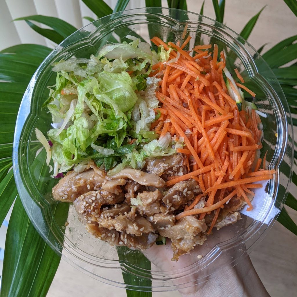The yumami teriyaki bowl opened up, in thirds there are lettuce, julienned carrot and chicken with sesame seeds.