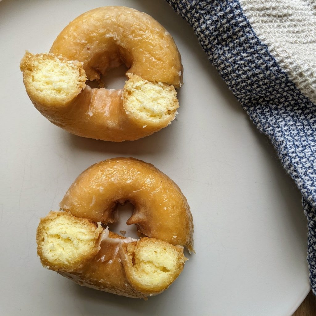 Two donuts cut open. The bottom donut looks more airy inside. 