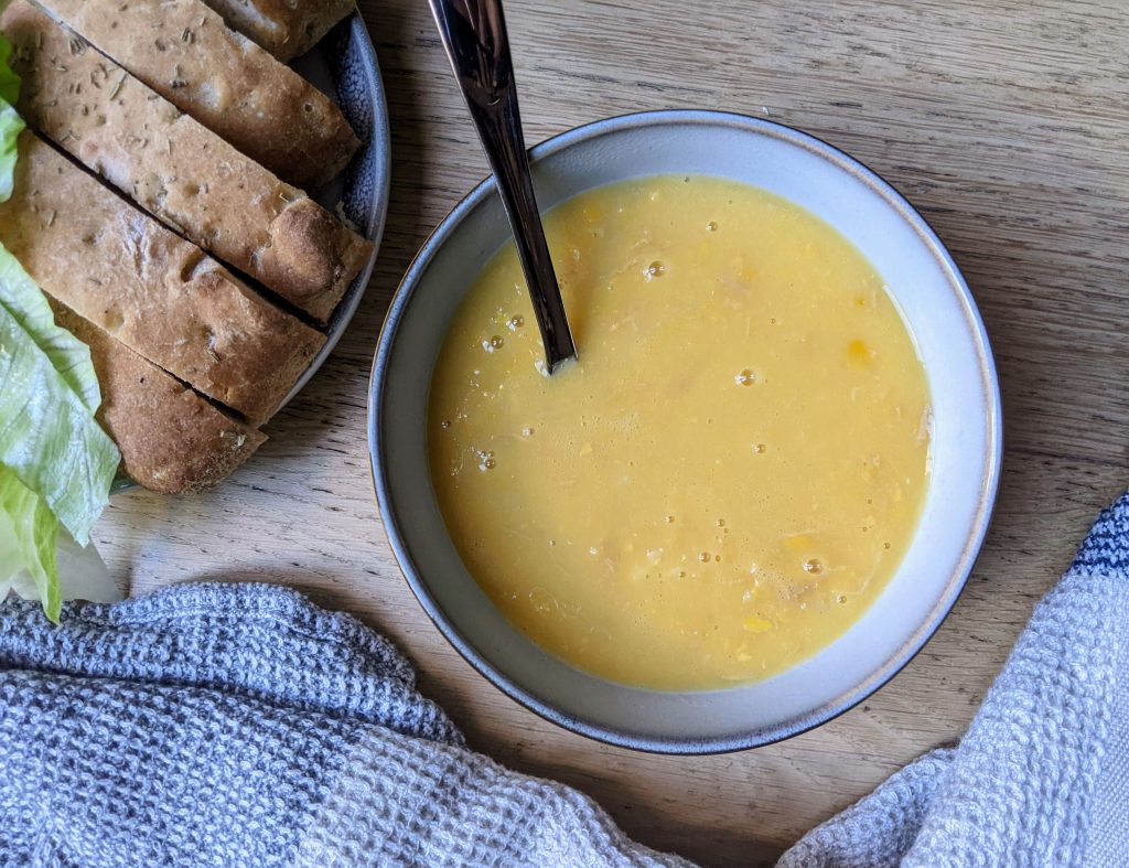 A bowl of hart and soul chicken and corn soup with a side of gluten free focaccia. 