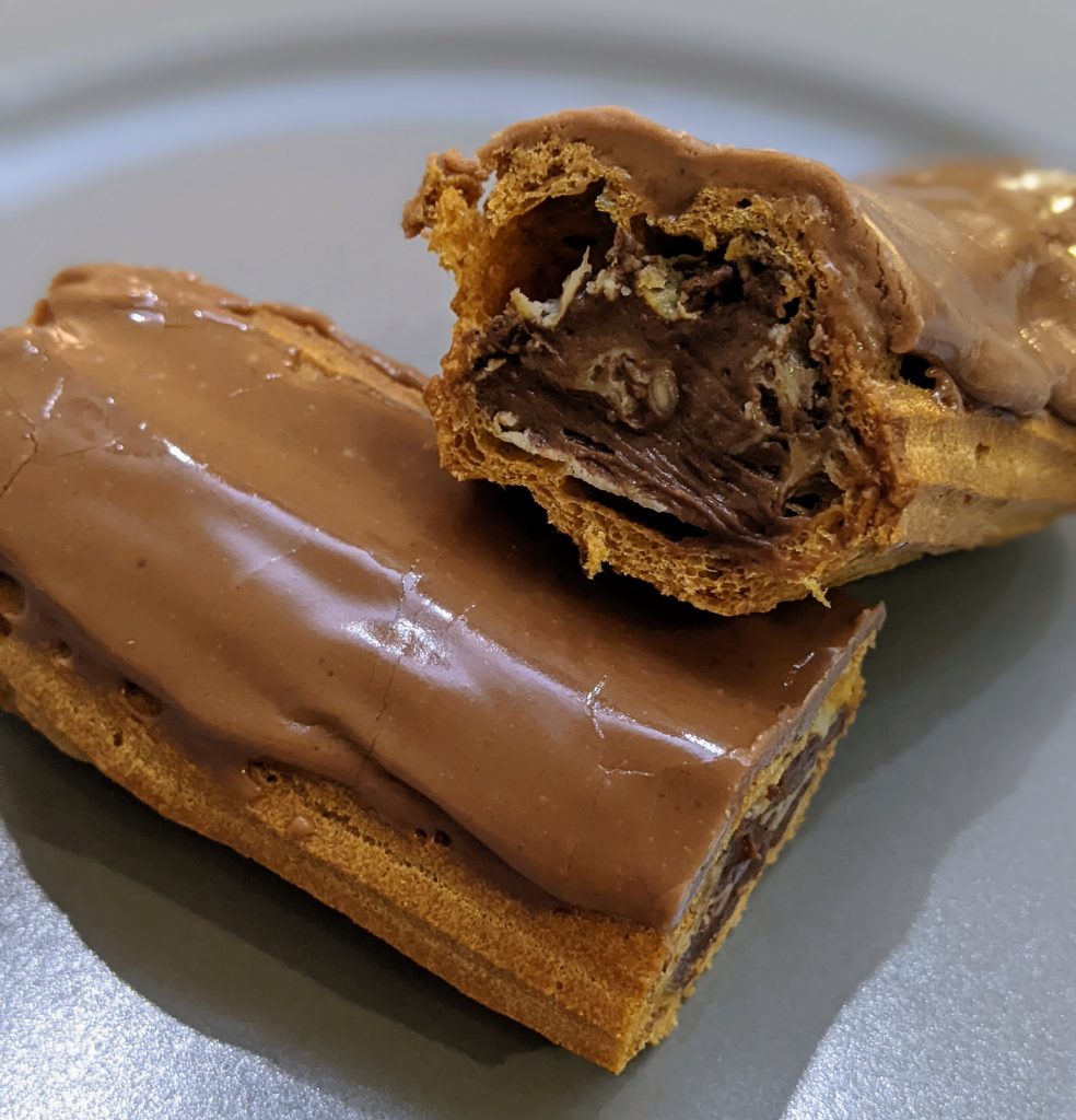A gluten free choux pastry eclair. Cut in half to see the chocolate custard inside.