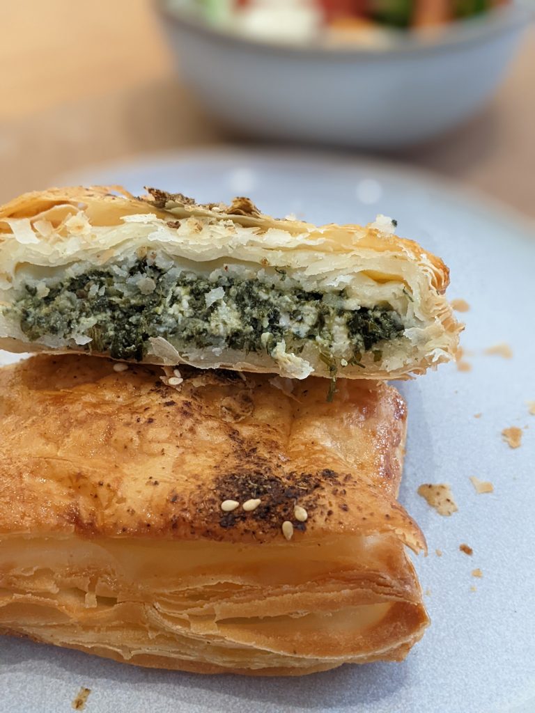The inside of the spinach and feta feuillete by Sebastian Sans Gluten. Inside is finely chopped spinach and pieces of feta densely packed inside.