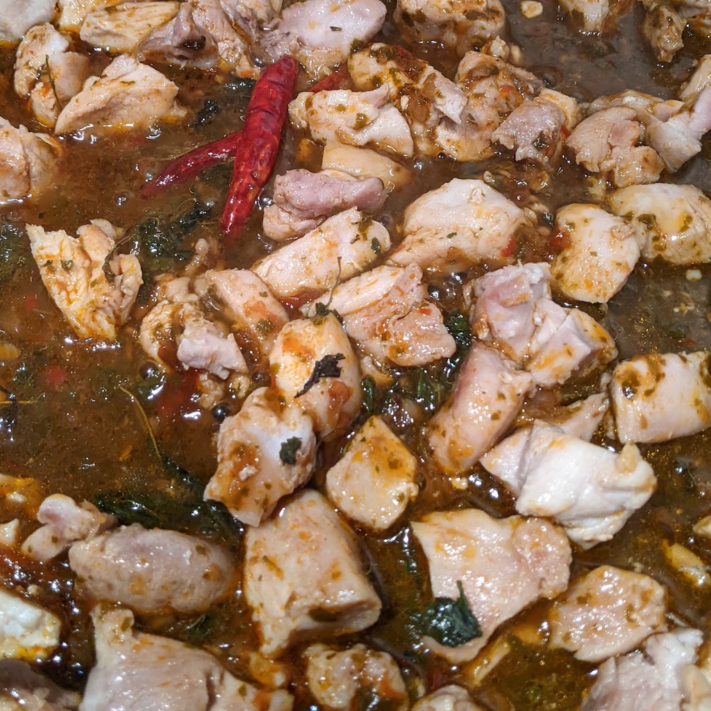 A close up of Mr Chen's Thai Basil chilli sauce with chicken in a pan. 