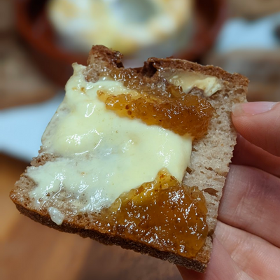 A piece of bread smeared with baked camembert and fig jam.