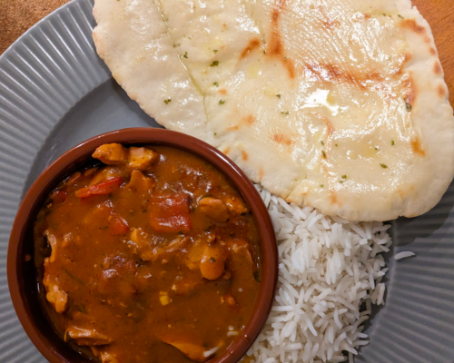 Gluten free naan on a plate with rice and curry.