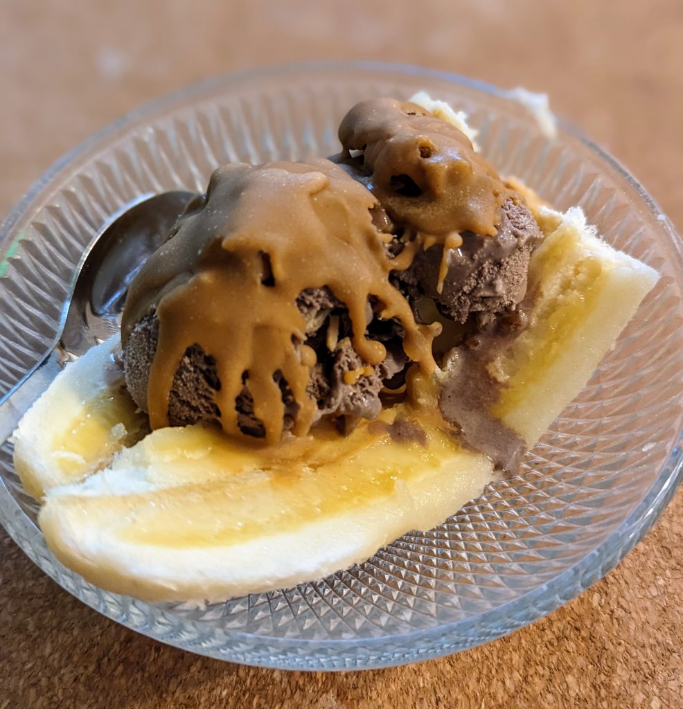 A bowl with banana, chocolate ice cream and peanut butter ice magic shell.