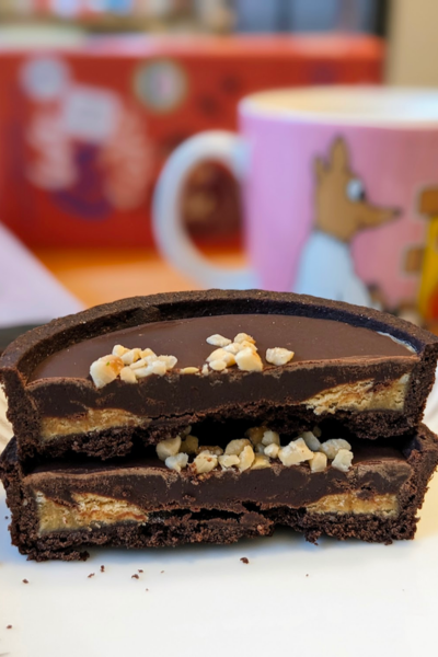 Inside view of we love cake chocolate caramel tart. Caramel can be seen at the edges with a thick layer of ganache in the middle. 