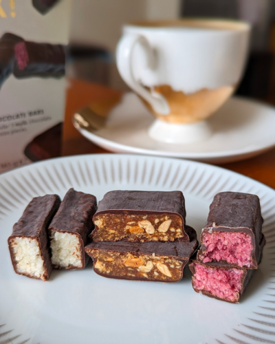 Three chocolates showing their inside. One is pure white, one is caramel and peanut chunks and the other is a natural pink colour.
