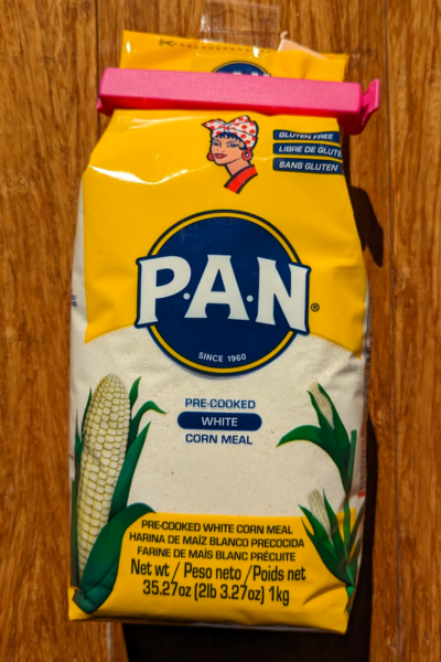 A bag of P.A.N white arepa flour with a large pink clip sealing it shut.