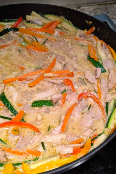 A frying pan with thai green curry cooking