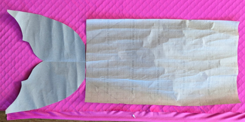 A paper template for a DIY mermaid tail on top of pink fabric