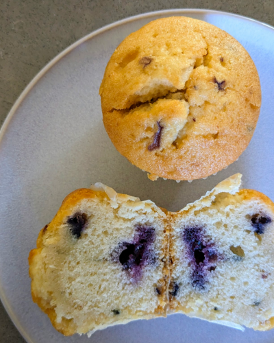 Top view of two muffins, one is cut in half to reveal a few blueberries inside.