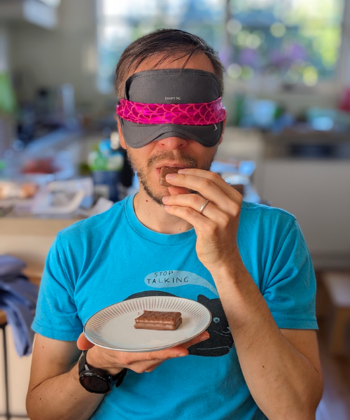 A blindfolded man eating a biscuit. 