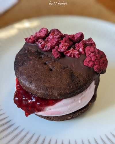a cookie sandwich with pink marshmallow filling, oozing jam and decorated with freeze-dried raspberry pieces