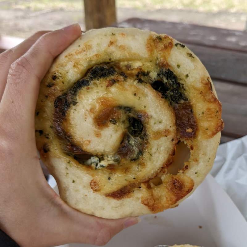 A hand holding a cheese spinach scroll